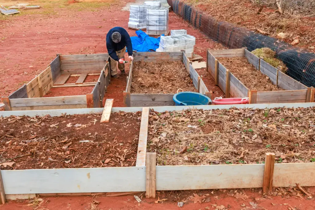 Man drilling together a new garden bed frame outdoors