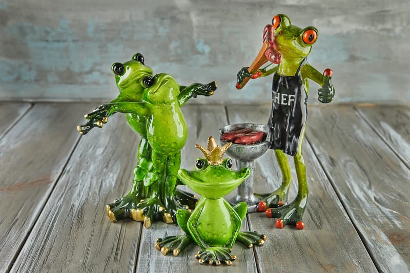 Set of small ceramic frog figurines on a wooden surface