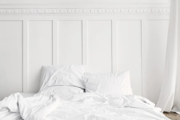 Clean girl aesthetic room ideas: a minimal bedroom with crisp white bed linen against a plain wall