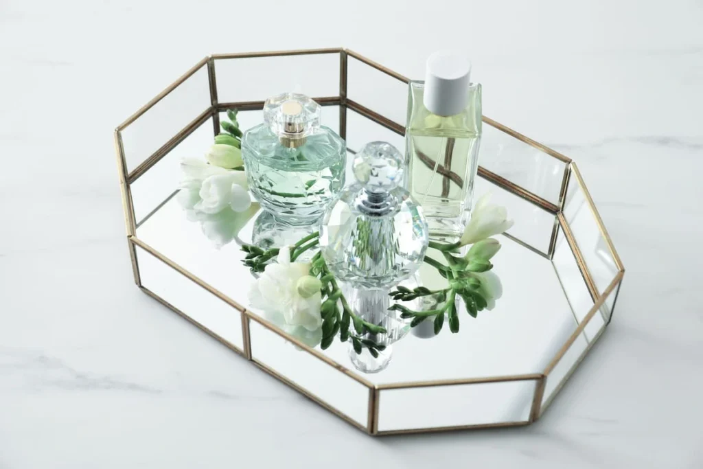 Coquette room decor detail: perfume bottles and flowers on a tray on a white table