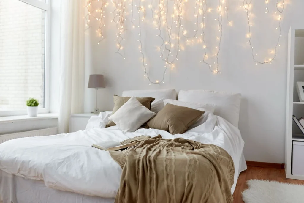 Coquette room decor for a small bedroom: a cozy bed lit by warm white string lights