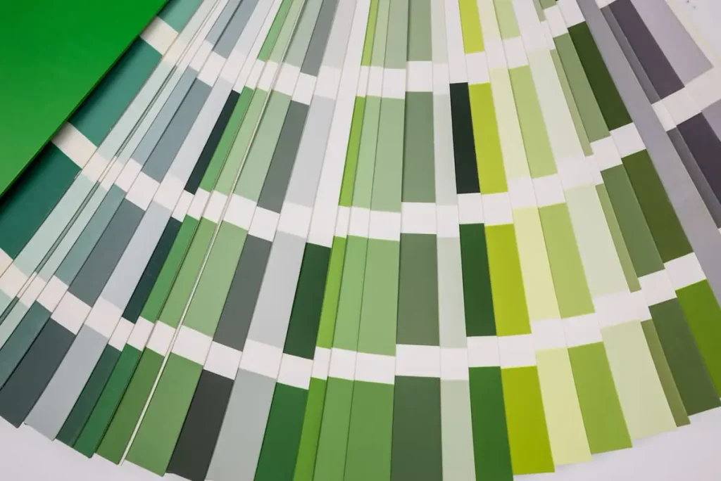 Fan of paint swatches in shades of green, from pale sage to deep forest green