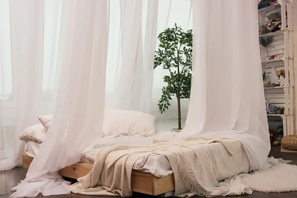 Floor-length curtains beside a cozy bed in a Nancy Meyers style bedroom