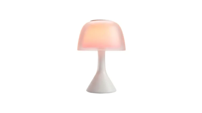 Mushroom-shaped table lamp casting a warm glow in a goblincore bedroom.
