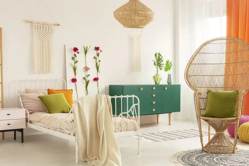 Bedroom with a handmade flower board, macrame and a peacock chair