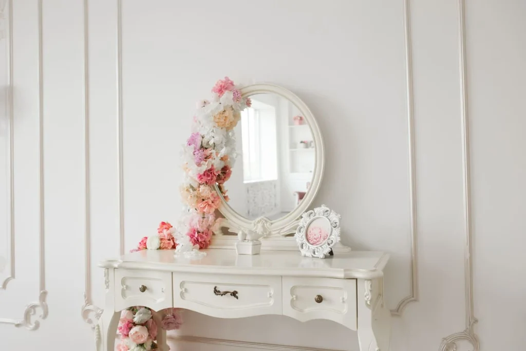 Vintage vanity table with a round mirror and flowers in a bright white room