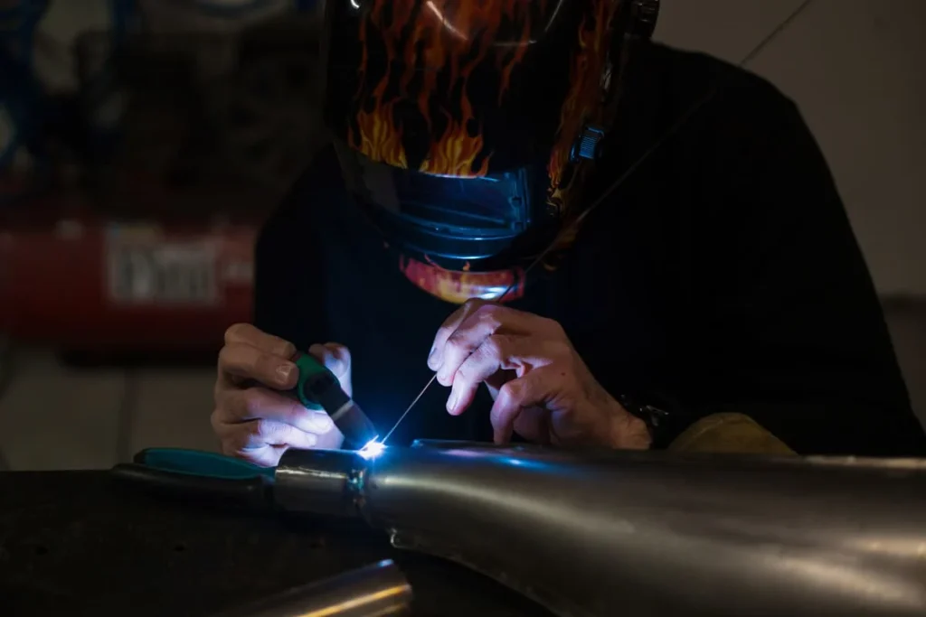 Man welding with an argon machine inside a home garage