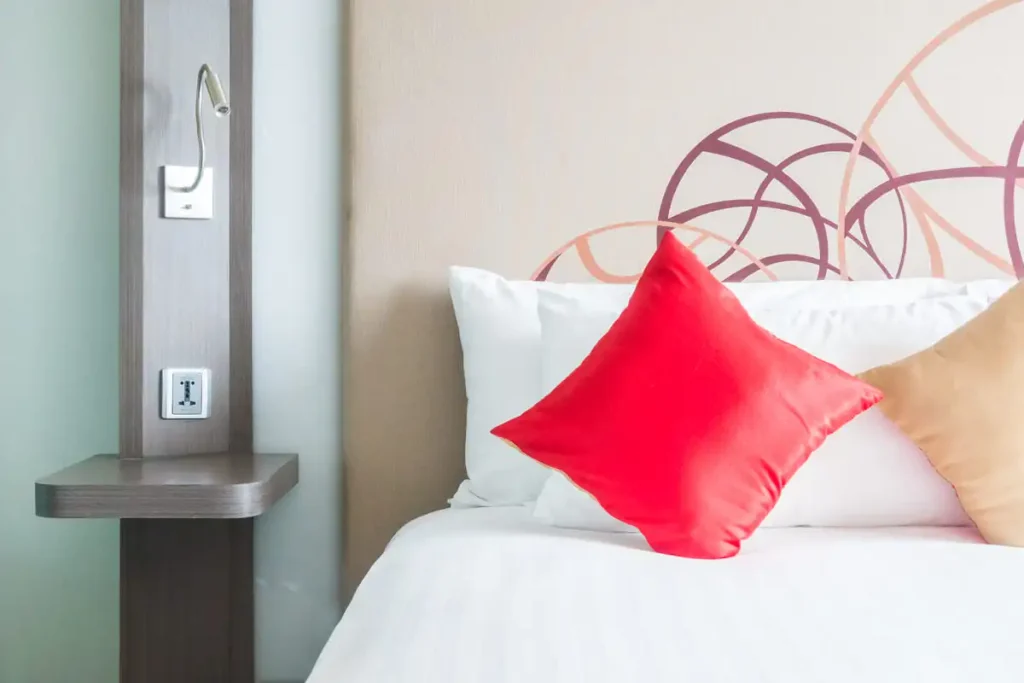 White bed with a single red cushion, the warm white and red look for an adult bedroom