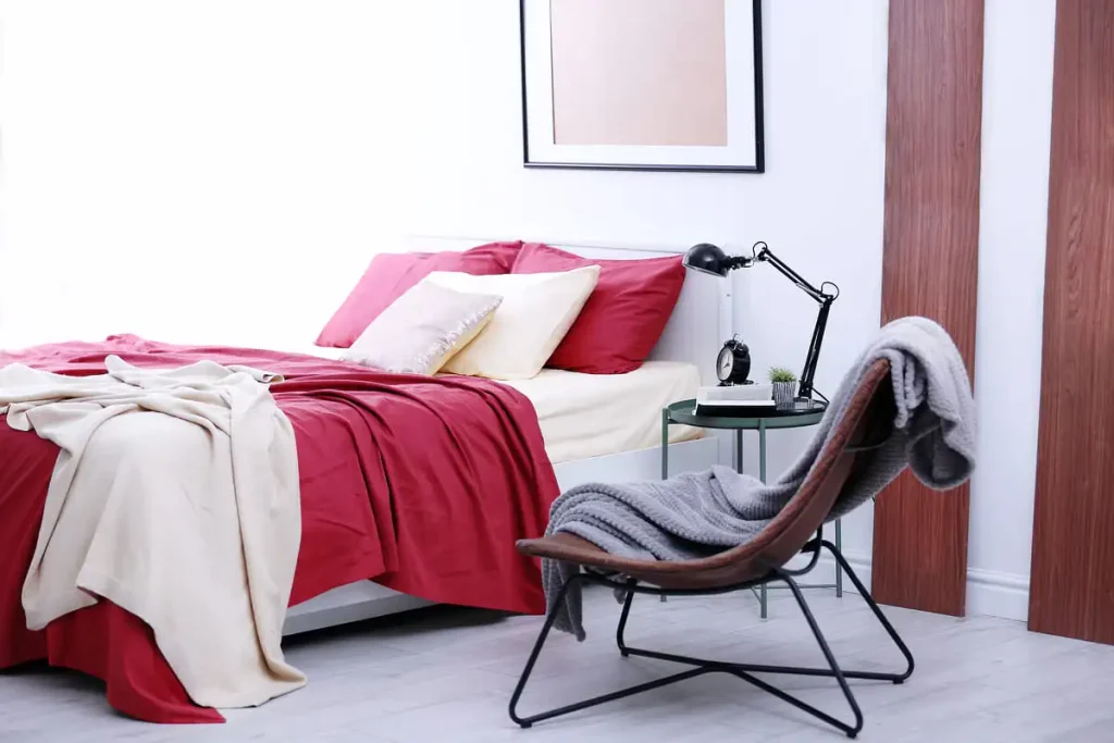 Bed with burgundy bedding in a light-walled bedroom