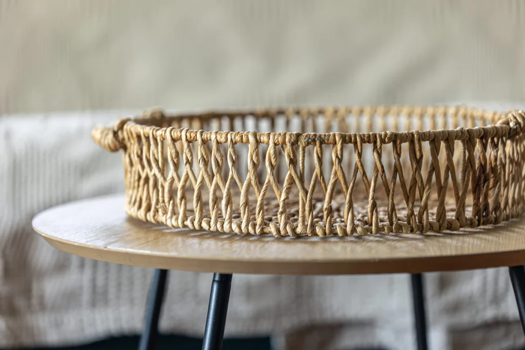 Round woven wicker basket on a wooden table adding texture to a neutral bedroom